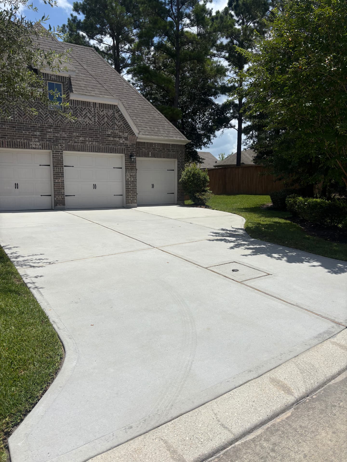 Driveway freshly washed in front of a brick home — pressure washing in Montgomery, TX