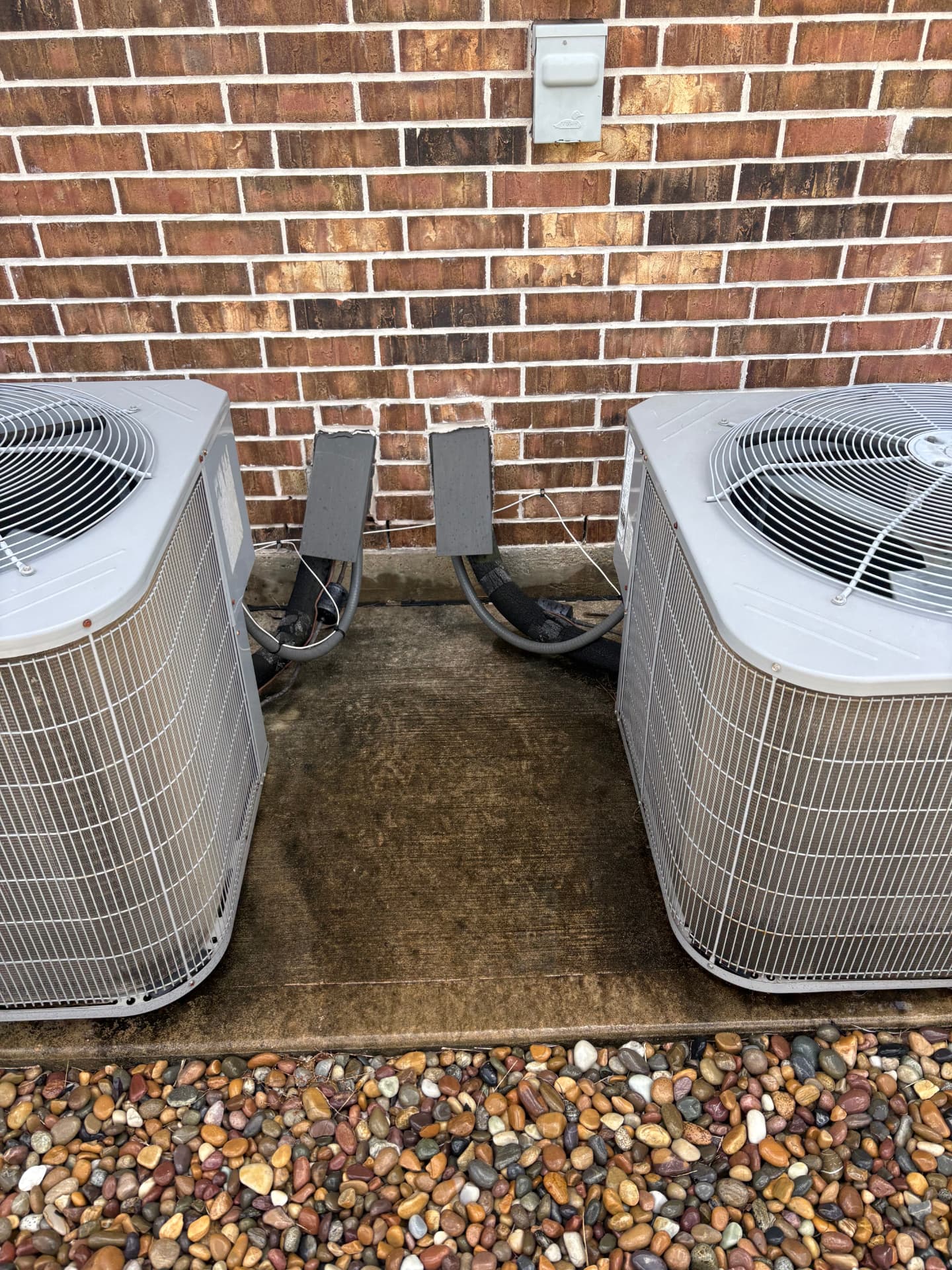 Concrete pad between two air conditioning units covered in grime — pressure washing in Montgomery, TX