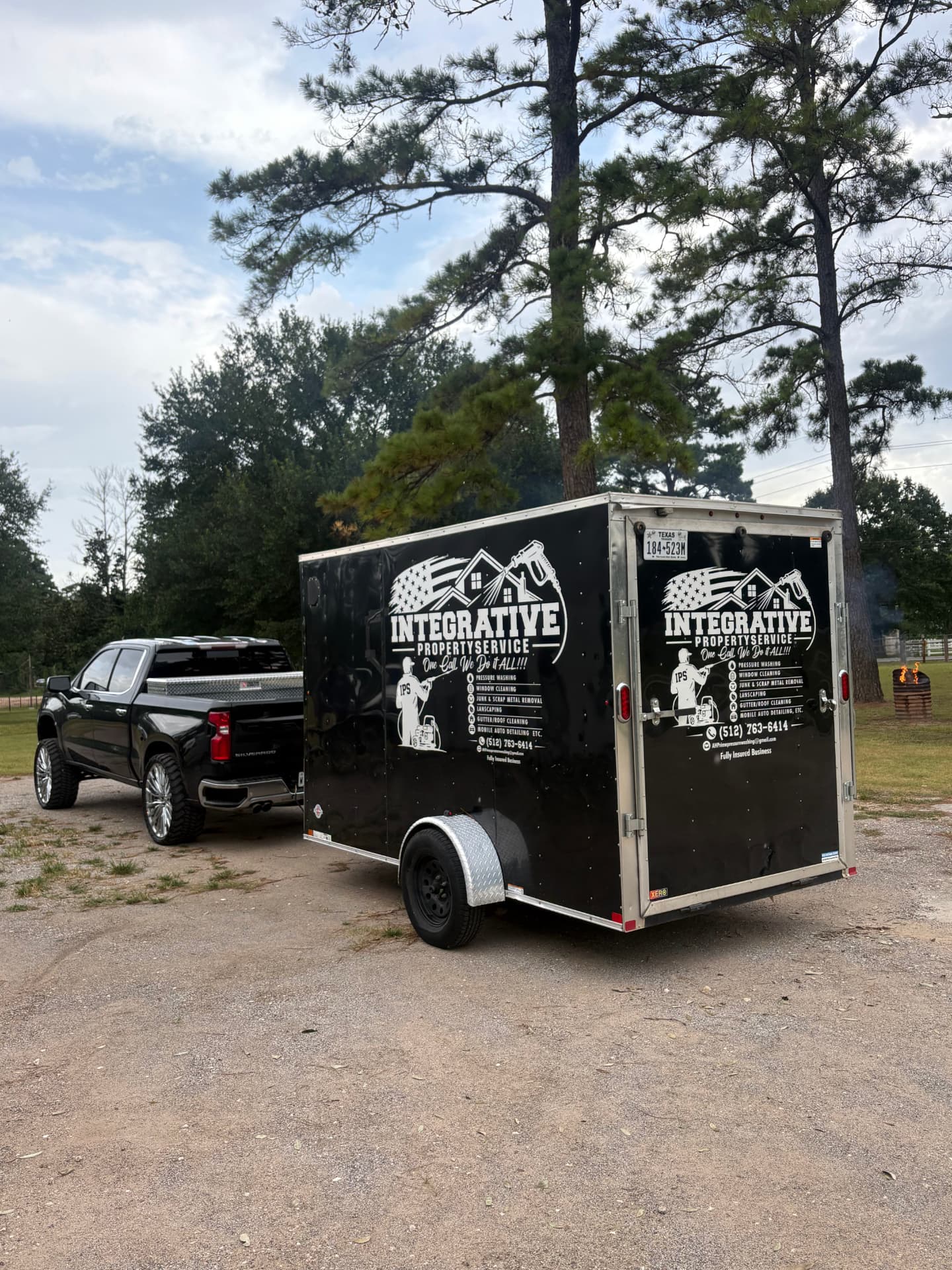 Integrative Property Services branded equipment trailer hitched to a black pickup truck — Integrative Services, Montgomery TX