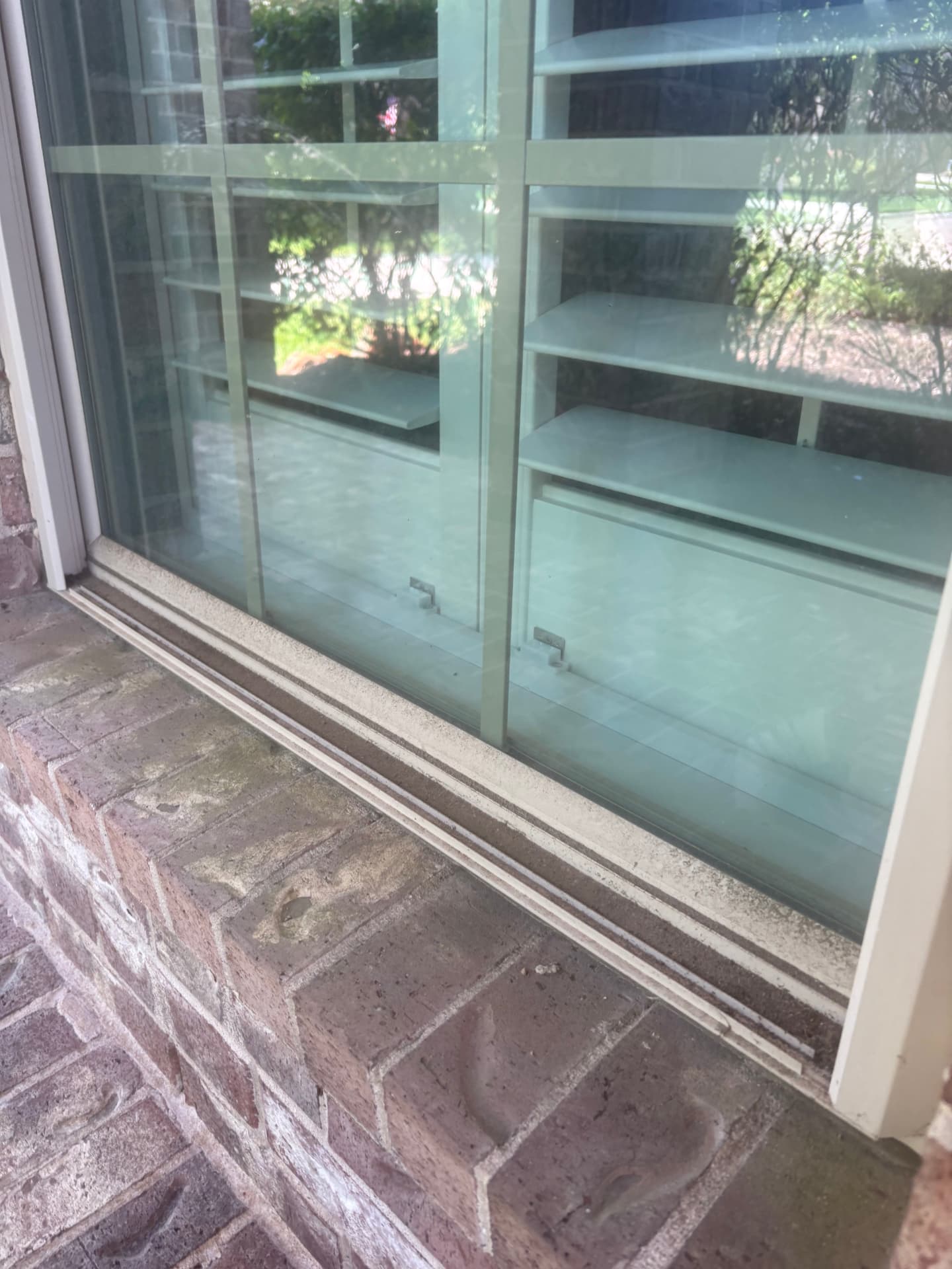 Window on a brick home with dirt along the sill — pressure washing in Montgomery, TX