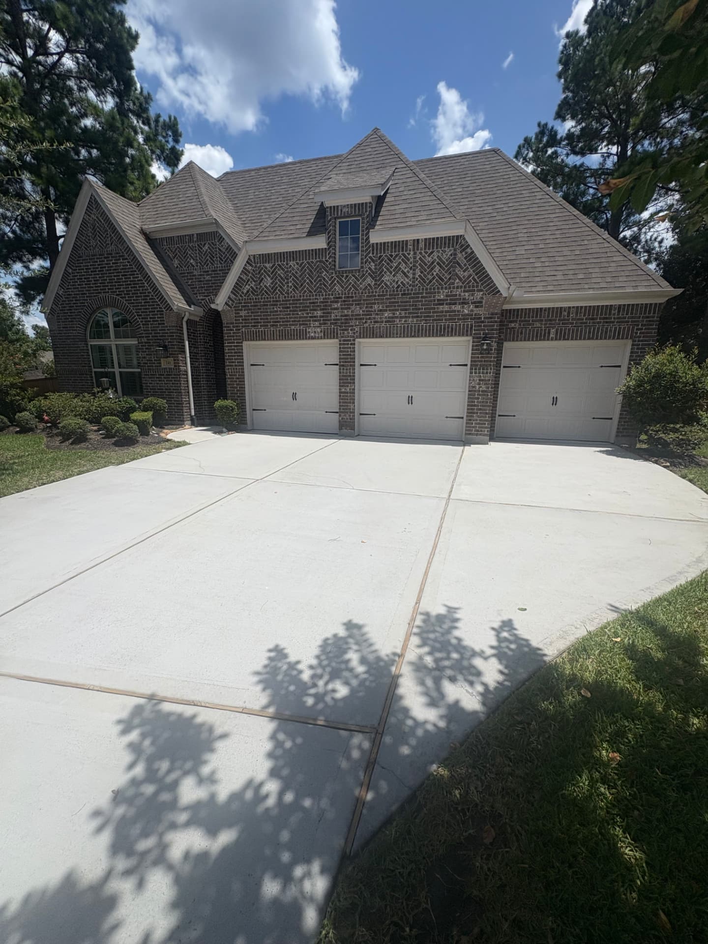 Concrete driveway washed clean in front of three white garage doors — Integrative Services, Montgomery TX