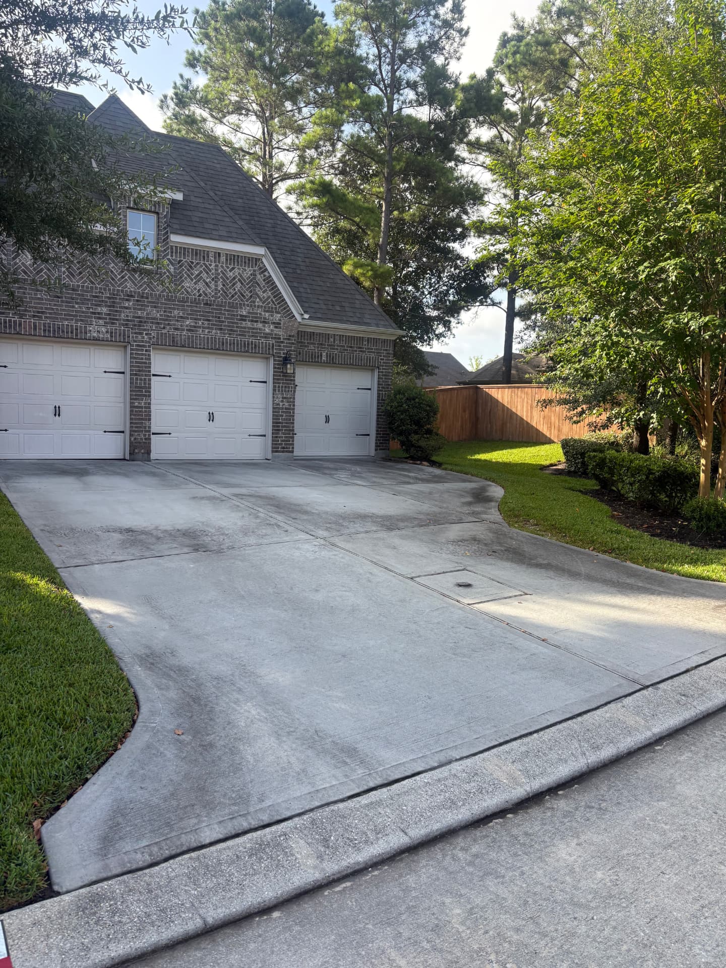Driveway between a brick home and manicured lawn before a wash — pressure washing in Montgomery, TX