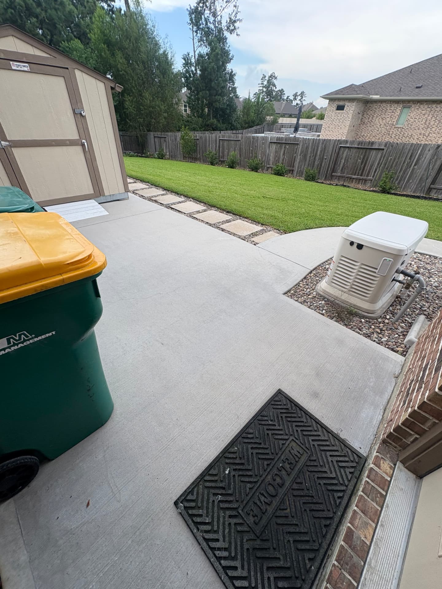 Clean concrete patio with stepping stones toward a green lawn — Integrative Services, Montgomery TX