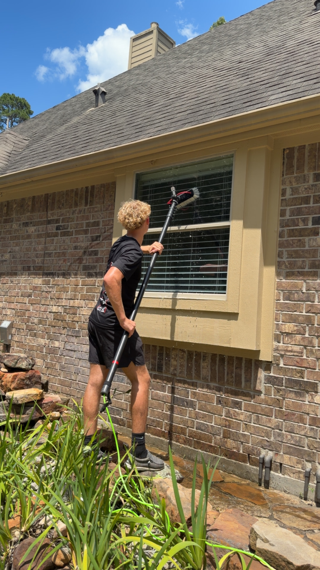 Integrative team member cleaning an exterior window on a brick home with a water-fed pole — Integrative Services, Montgomery TX